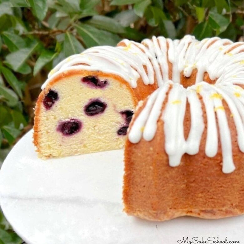 Lemon Blueberry Pound Cake, sliced, on a cake pedestal.