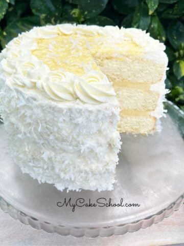 Sliced Coconut Cream Cake on pedestal.