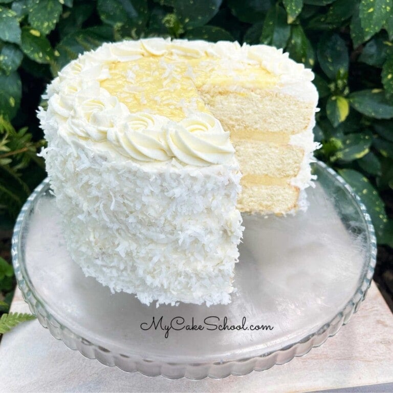 Sliced Coconut Cream Cake on pedestal.
