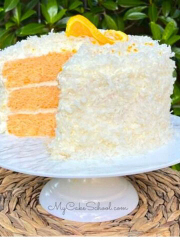 Orange Coconut Cake, sliced, on a cake pedestal.