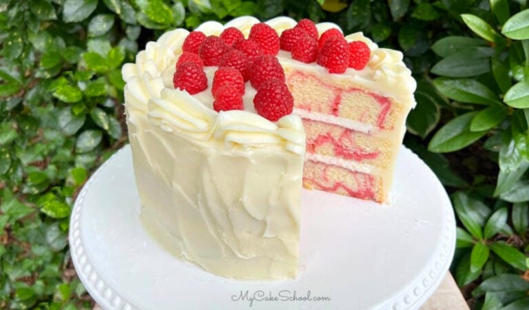 Sliced Almond Raspberry Swirl Cake on a white pedestal