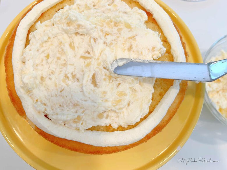 Adding pineapple cream filling to the cake