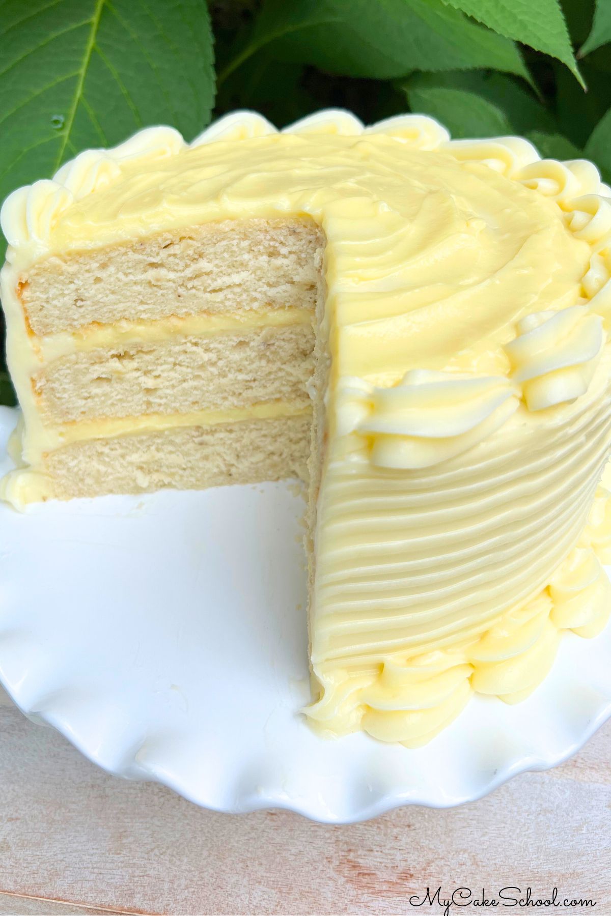 Banana Cream Cake, sliced, on a white pedestal outside.