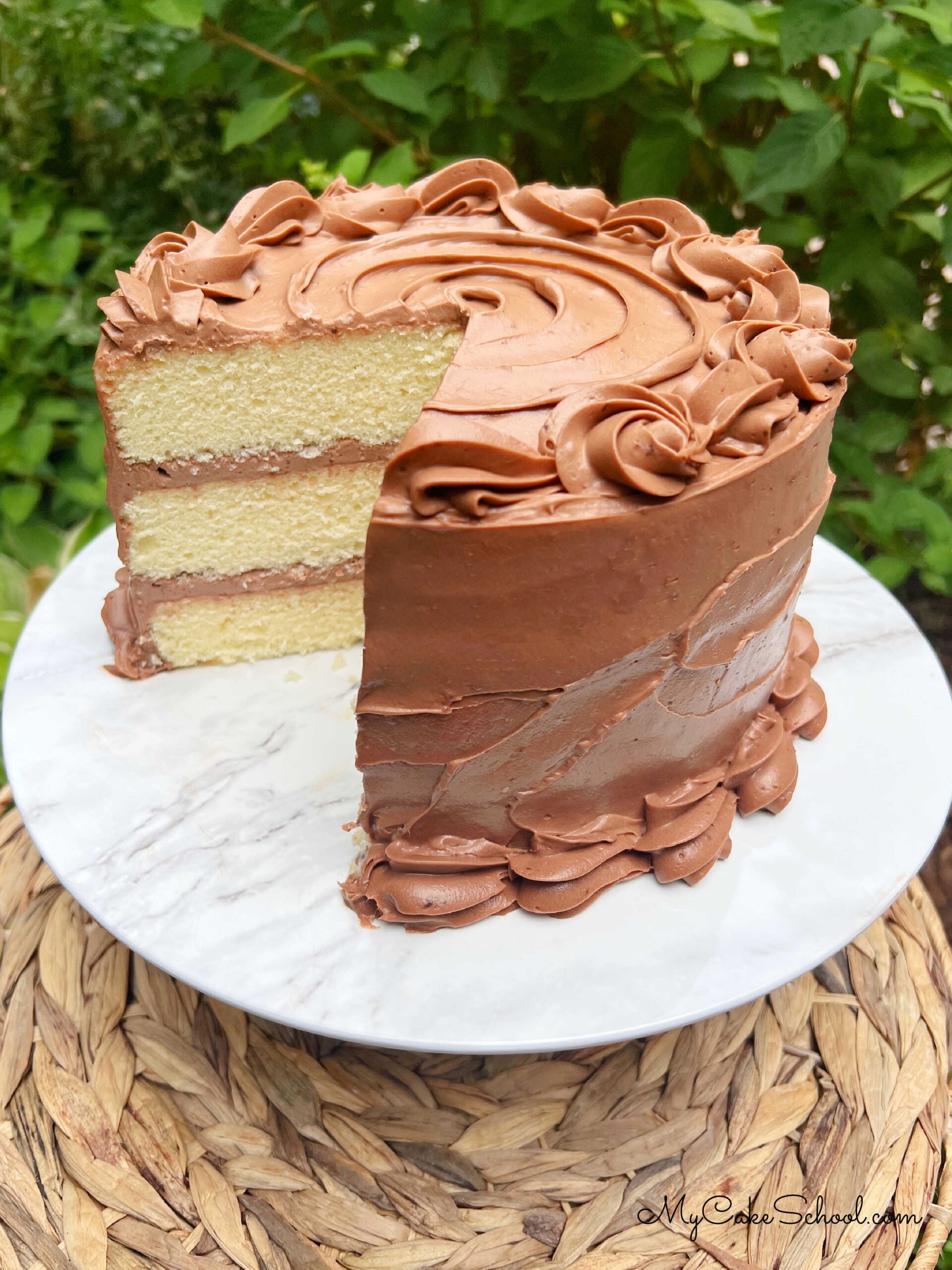 Sliced Yellow Velvet Cake with Chocolate Frosting on pedestal.