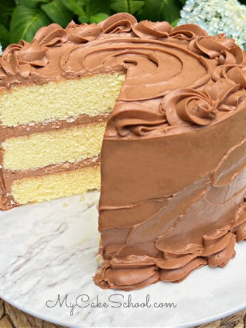 Sliced Yellow Velvet Cake with chocolate cream cheese frosting on a pedestal.