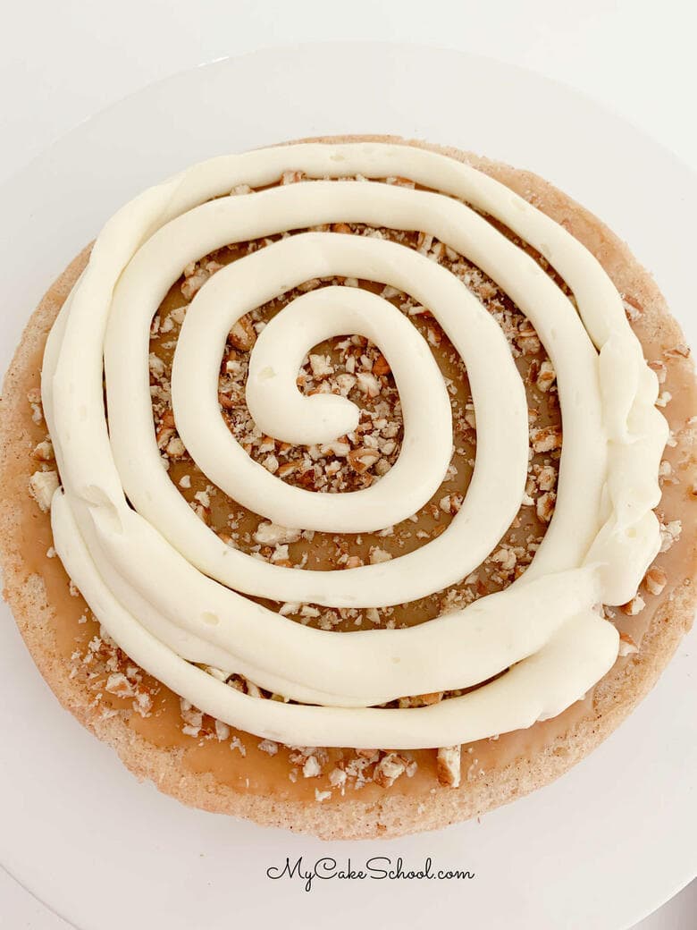Piping the cream cheese filling onto a cake layer