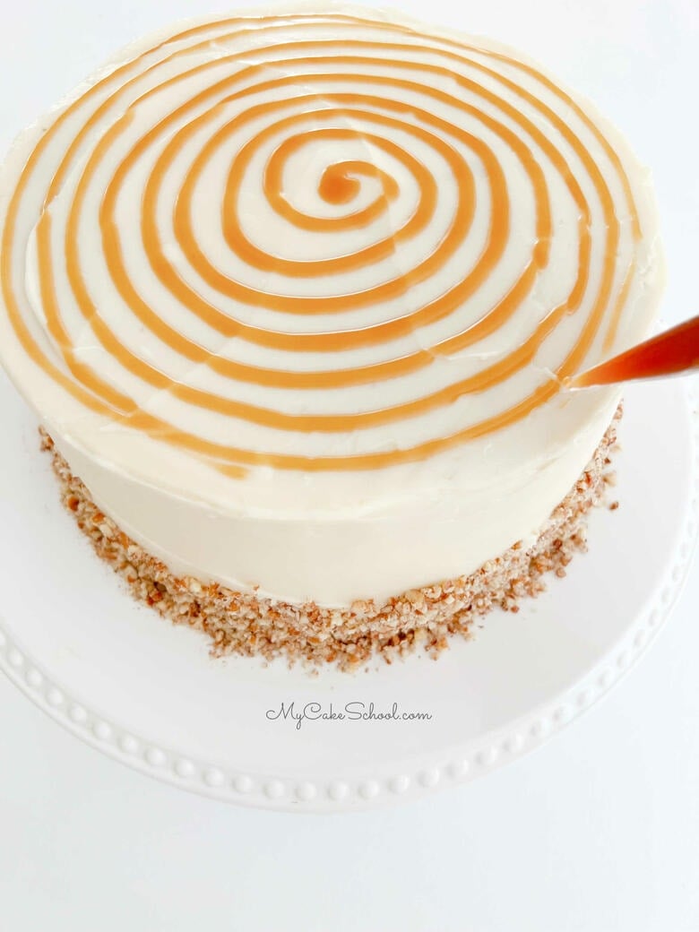 Piping a spiral of caramel on top of the freshly frosted cake
