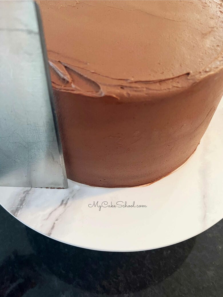 Smoothing the Frosting with a Bench Scraper around sides of the cake