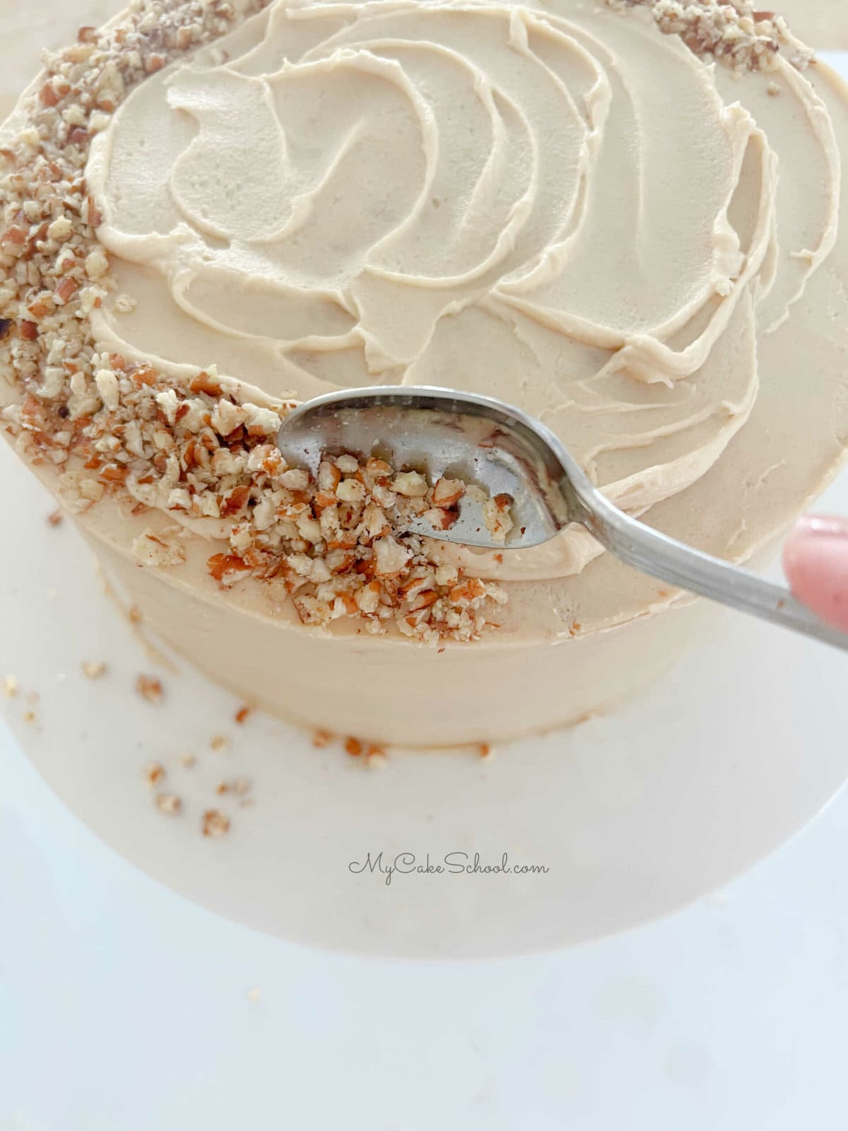 Adding crushed pecans around top edge of the cake