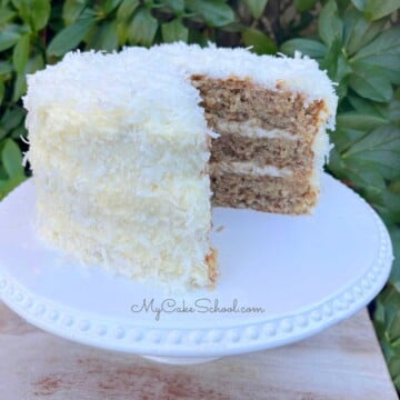 Sliced Coconut Hummingbird Cake on a cake pedestal.