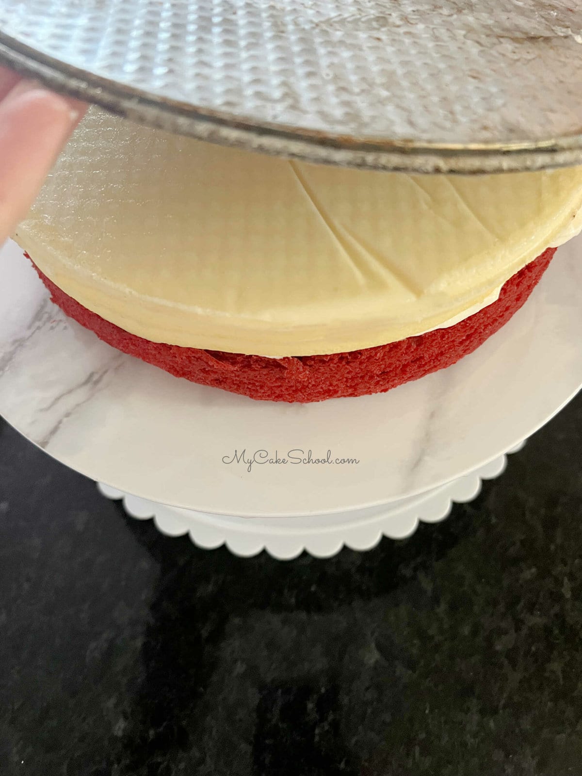 Removing base of springform pan from the cheesecake layer after flipping onto cake layer