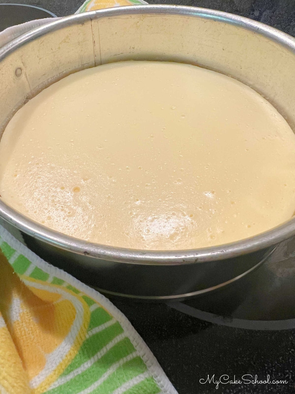 Freshly baked cheesecake layer cooling in the pan on countertop