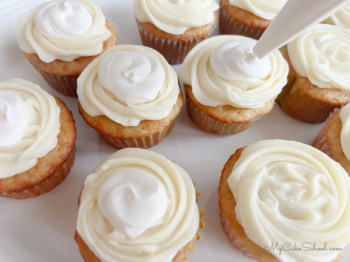 Piping dollops of Cool Whip onto our frosted cupcakes with a piping bag