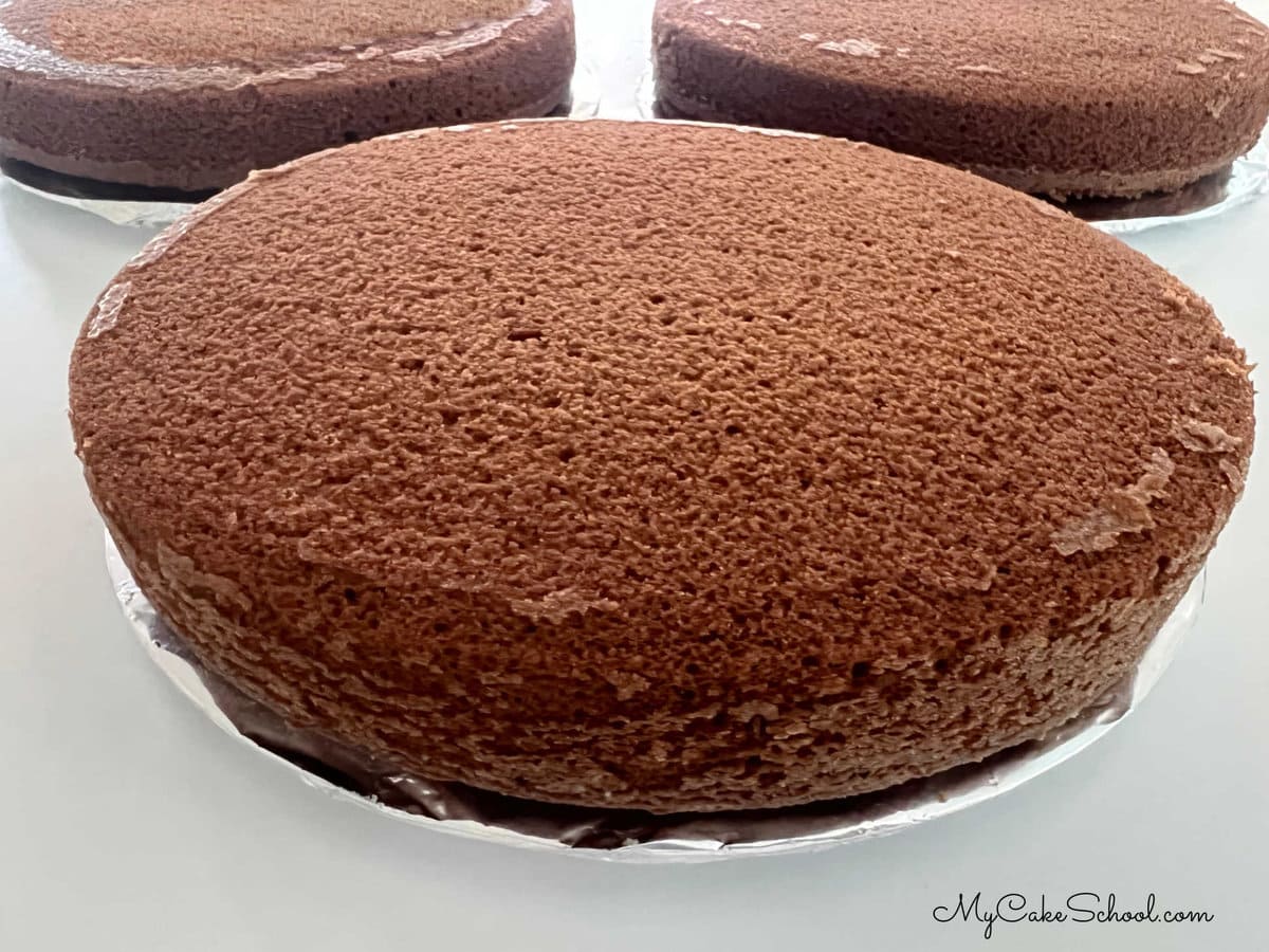 Three Chocolate Cake Layers resting on foil-wrapped cardboard cake circles