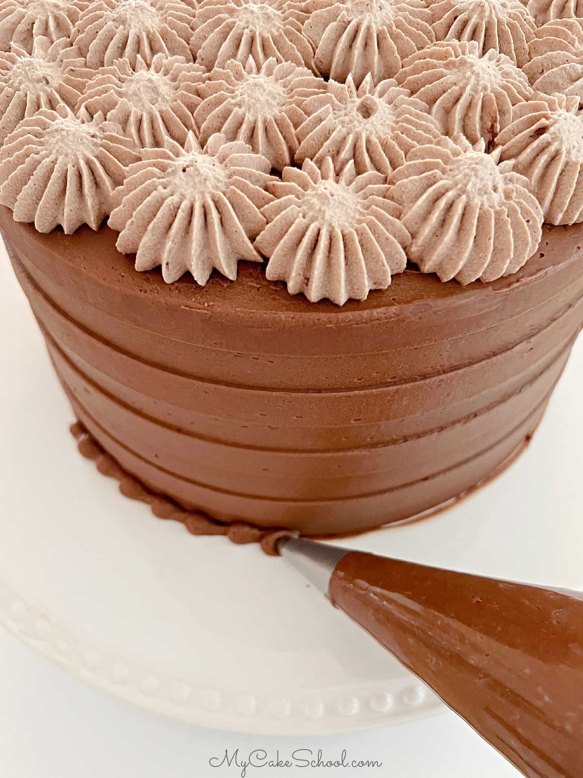 Piping a chocolate bead border around the base of the cake