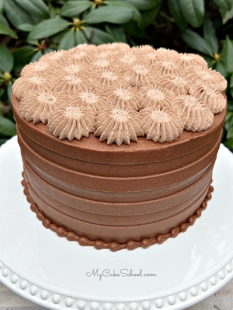 Photo of chocolate cake with combed chocolate buttercream around the sides and chocolate whipped cream star piping on top.