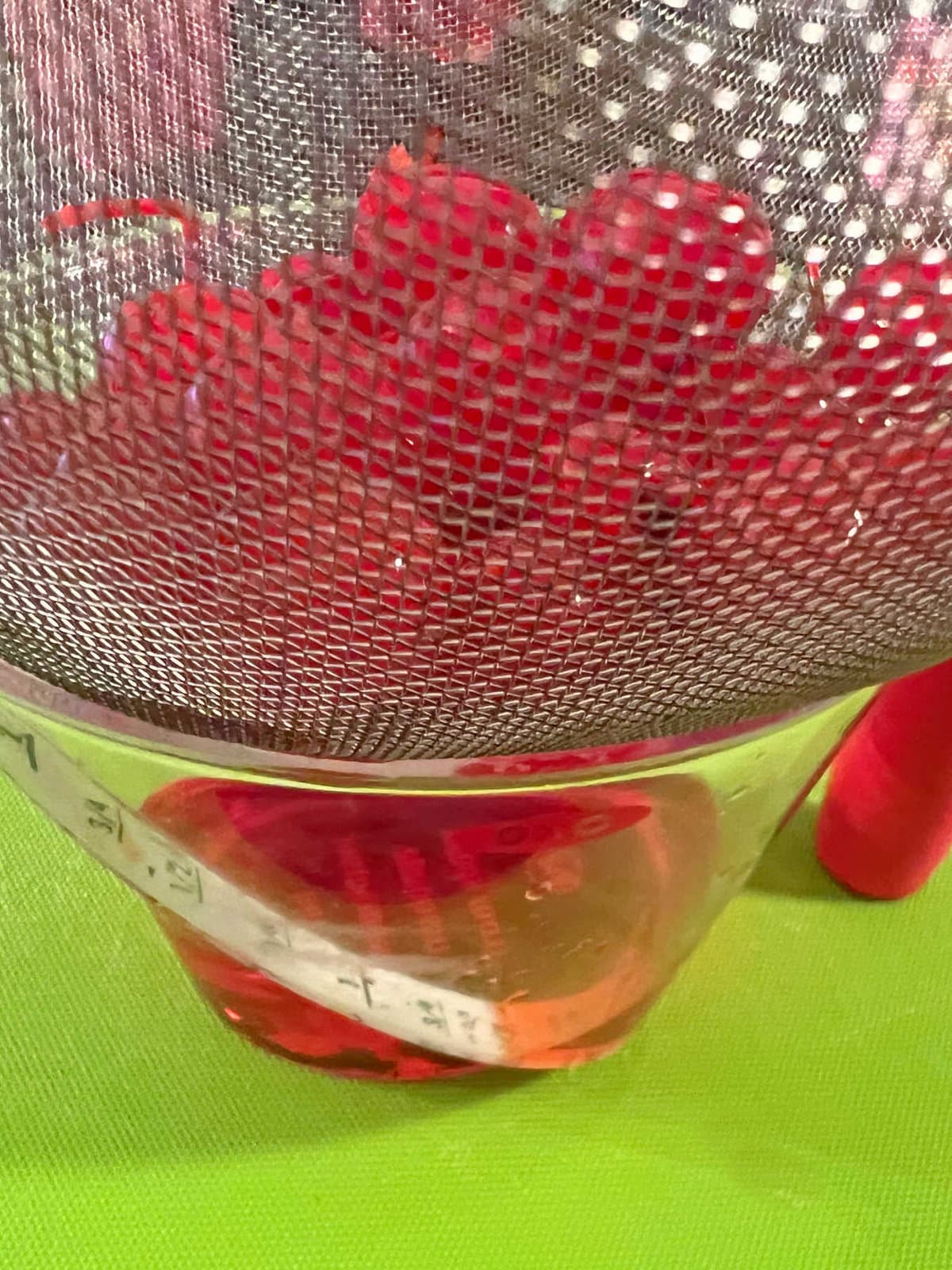 Draining maraschino juice from the cherries using a sifter over a bowl