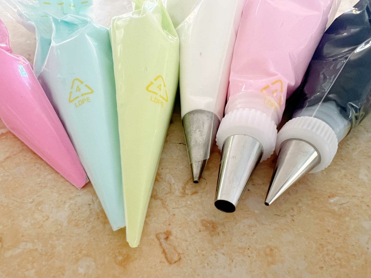 6 piping bags in a row, filled with different shades of buttercream