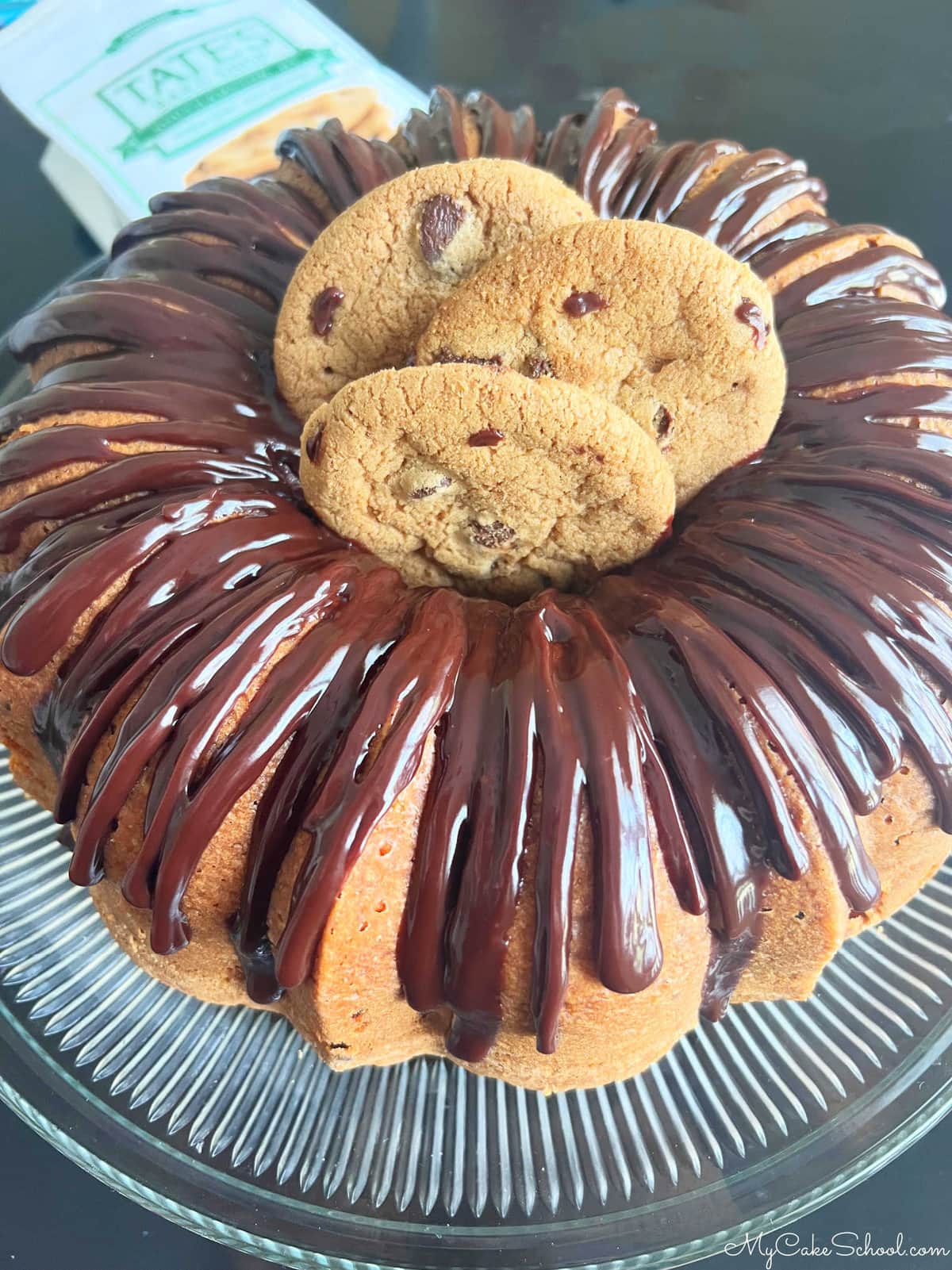 Chocolate Chip Cake on a Pedestal, topped with a chocolate glaze and chocolate chip cookies