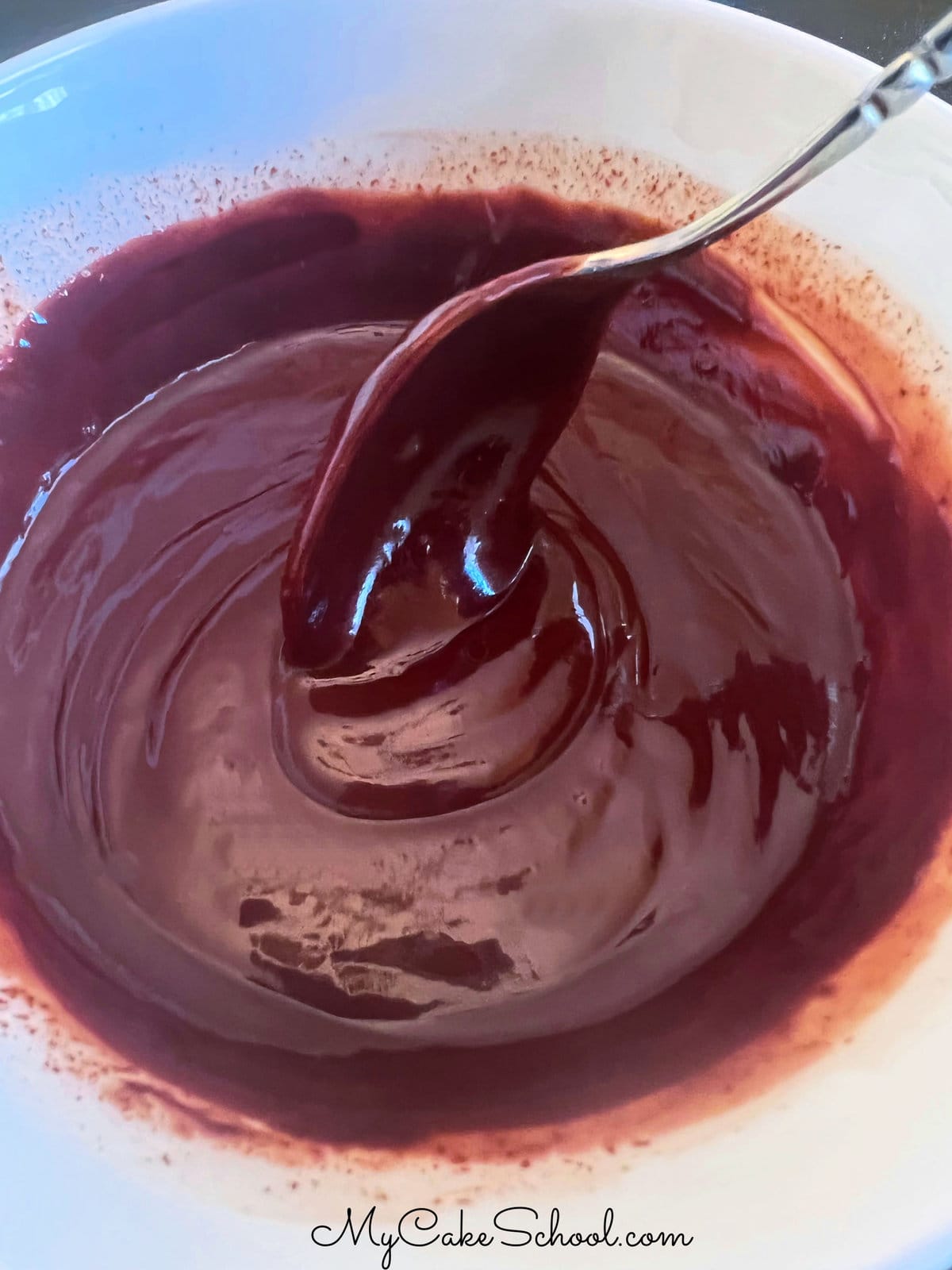 Spoon dipped in bowl of ganache