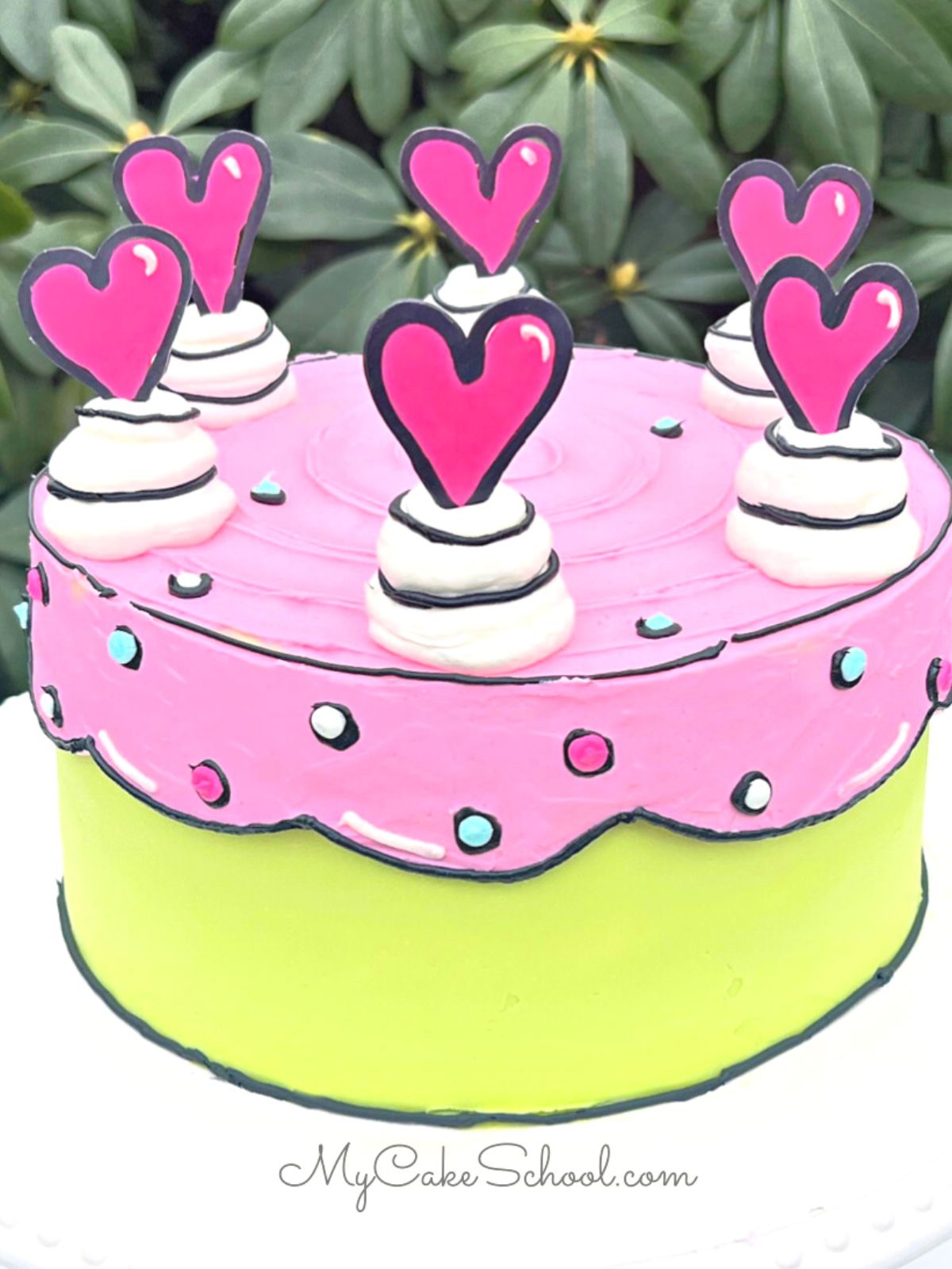 Cartoon Cake with pink and green frosting, topped with pink hearts.