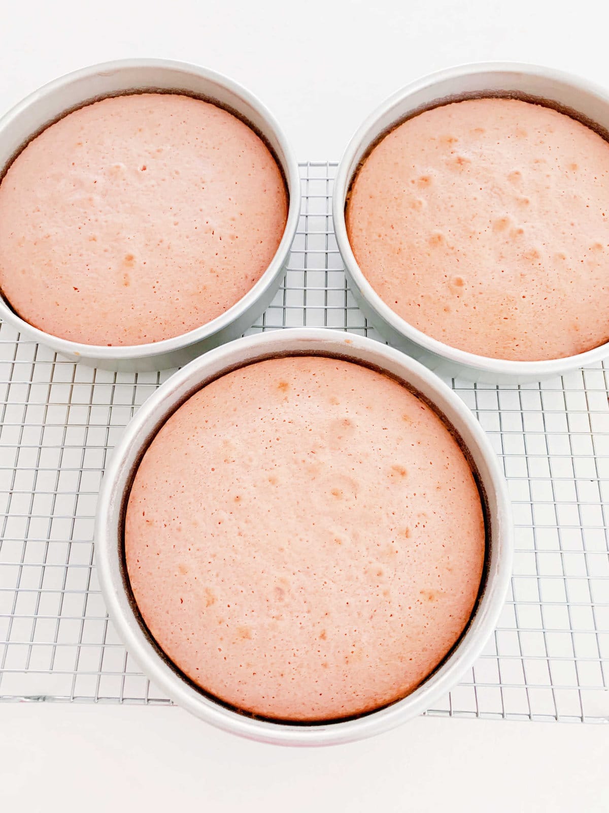 Three freshly baked cake layers, in pans