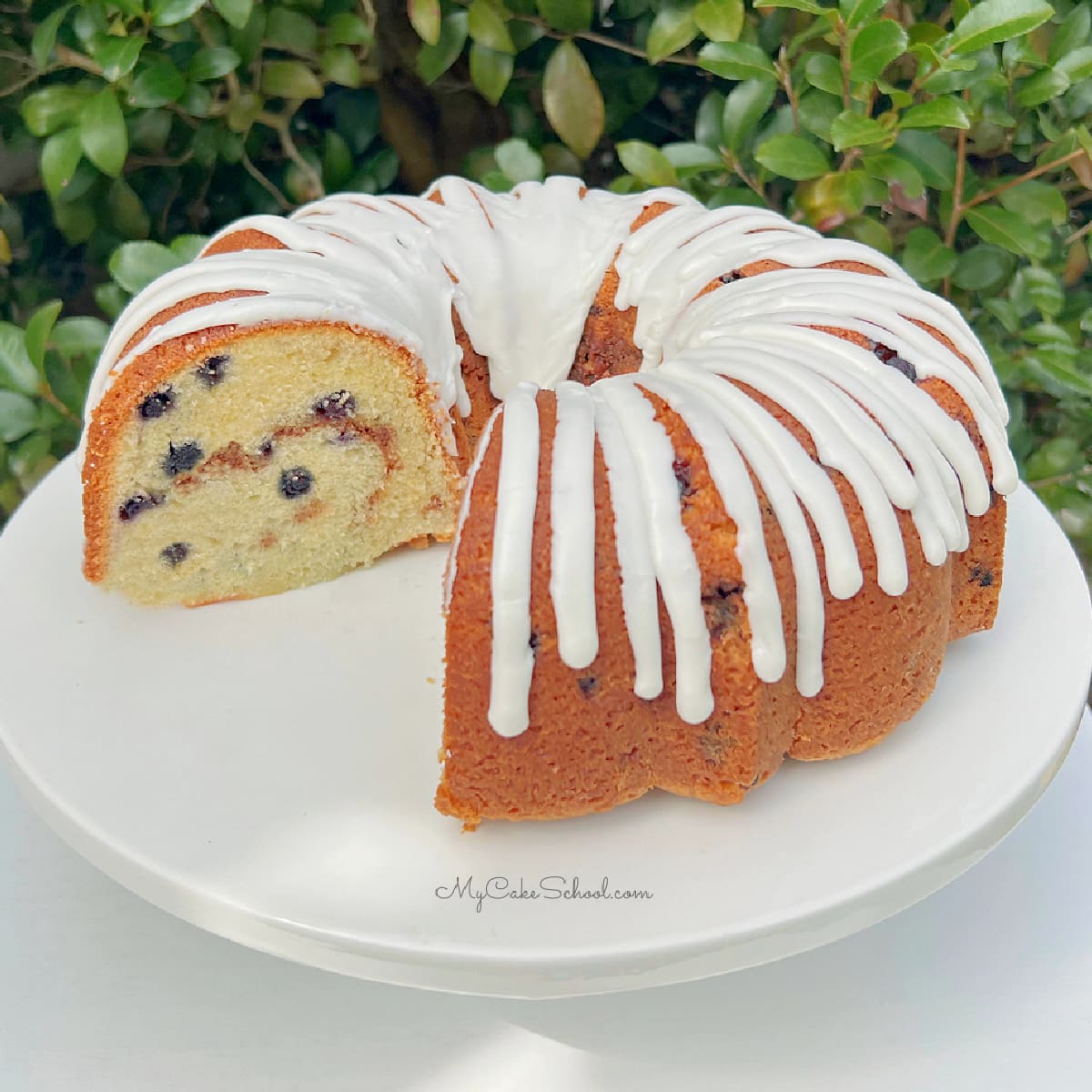 Glazed Blueberry Bundt Cake on a white pedestal