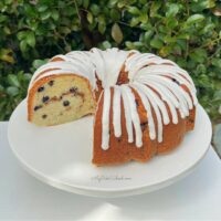 Slice blueberry bundt cake on white pedestal