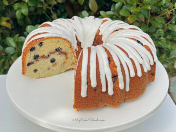 Slice blueberry bundt cake on white pedestal