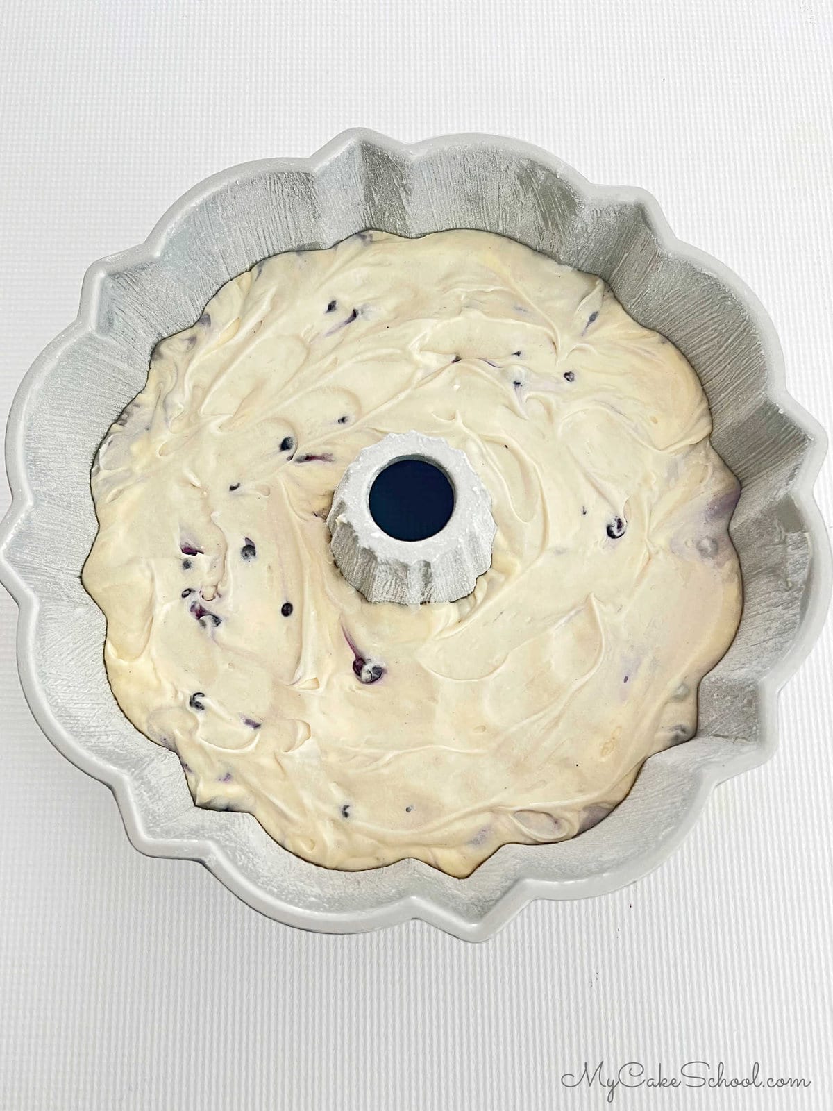Filled Blueberry Bunt Cake pan. The pan is layered with blueberry cake batter, a cinnamon mixture, and another layer of blueberry cake batter.