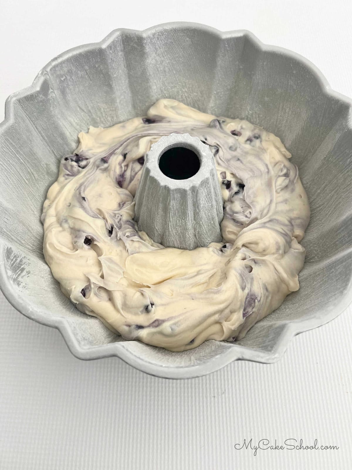 Half of blueberry cake batter in the prepared bundt pan