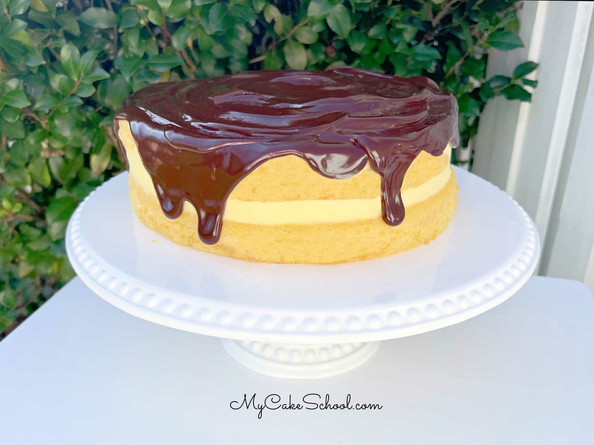 Boston Cream Pie resting on a white pedestal