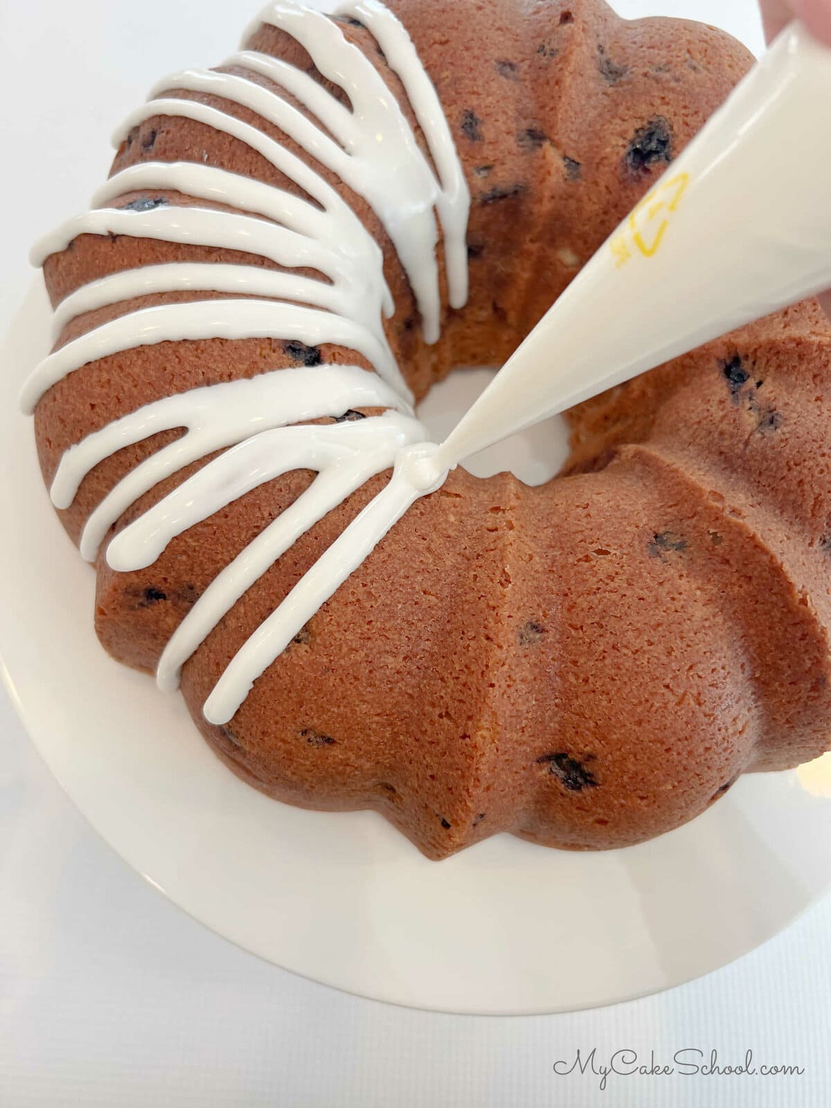 Piping an easy vanilla glaze onto cooled bundt cake with a piping bag