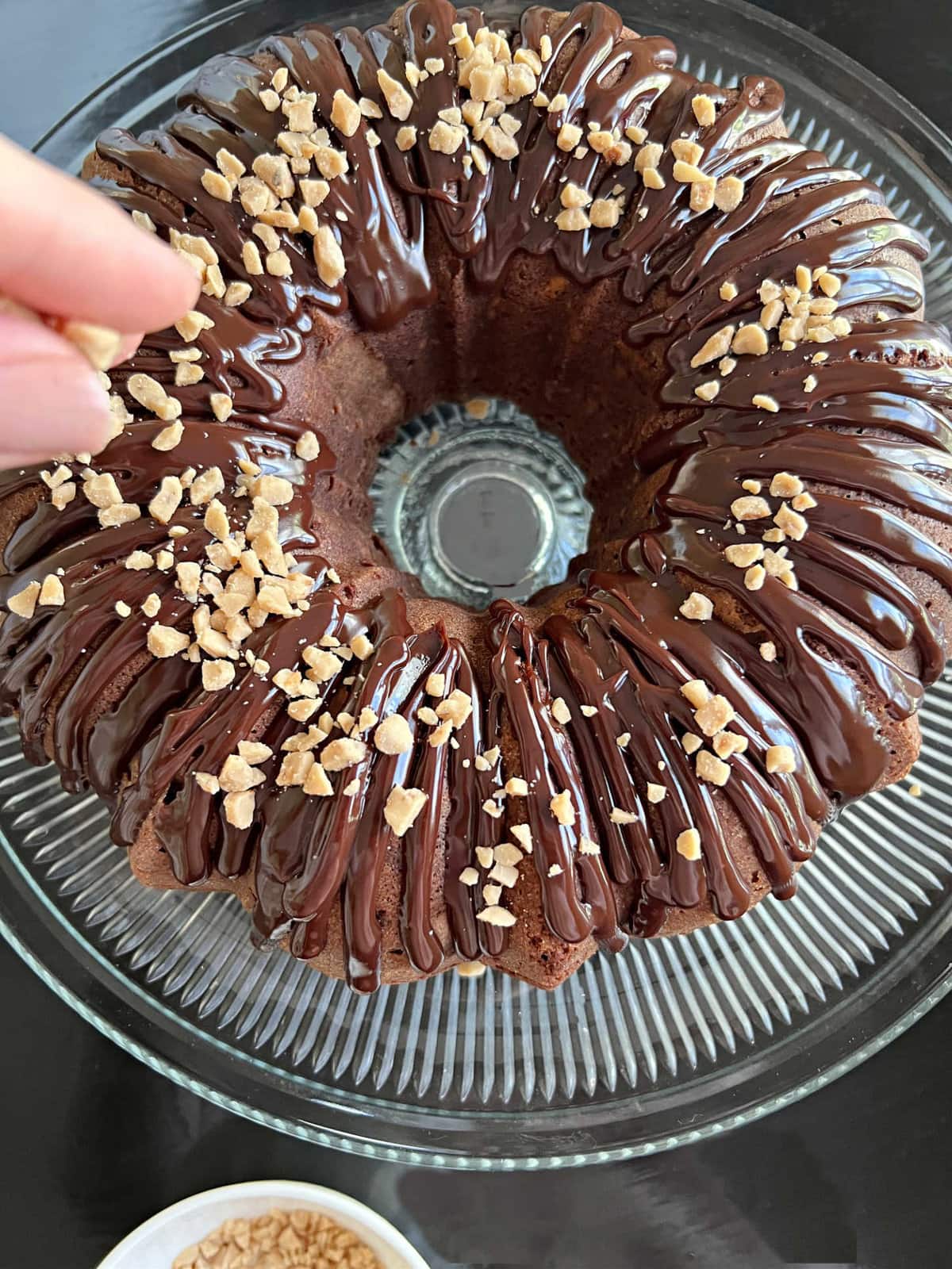 Sprinkle the top of the chocolate-glazed bundt cake with toffee bits