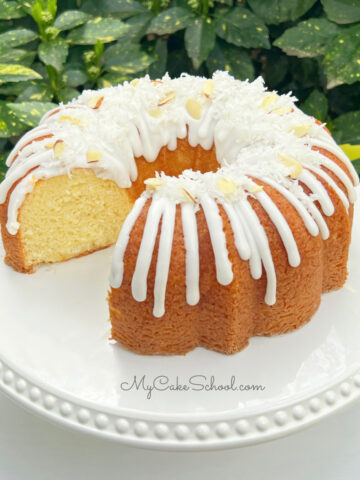 Almond Coconut Bundt Cake, sliced, on a white pedestal