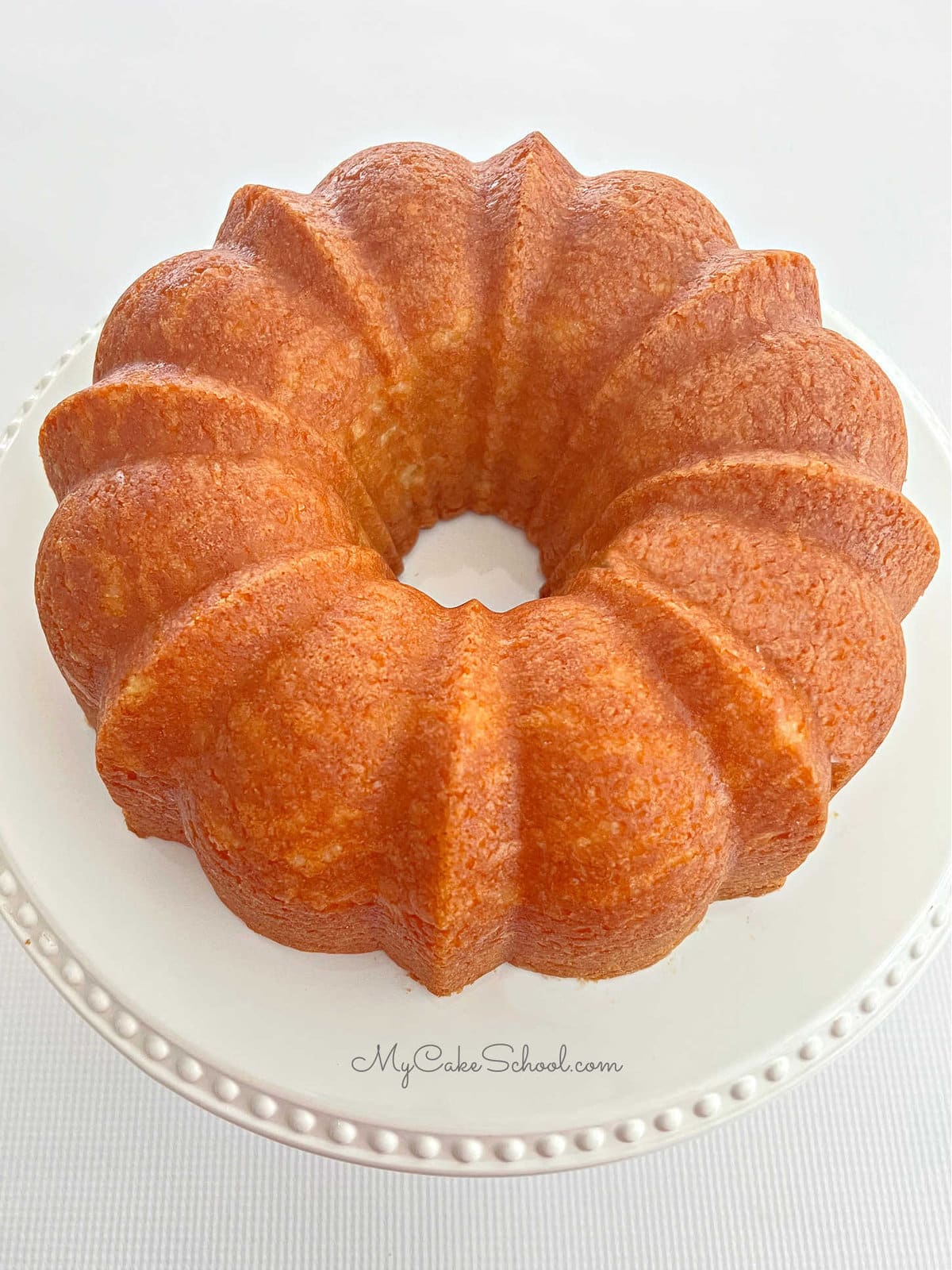 Freshly baked Almond Coconut Bundt Cake on white pedestal.