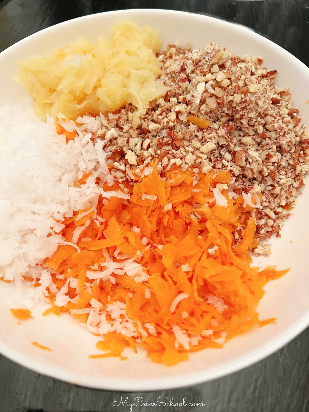 Bowl of grated carrots, coconut, crushed pecans, and crushed pineapple