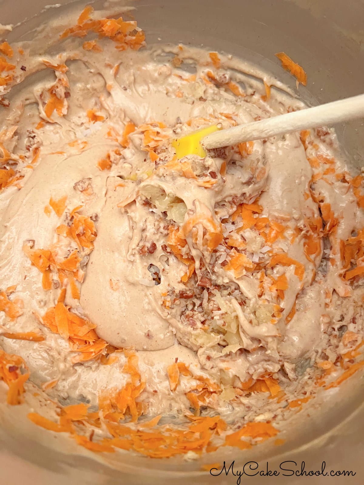 Folding carrots, coconut, pecans, and pineapple into the cake batter