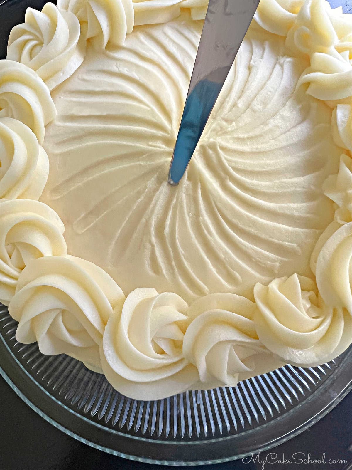 Adding design to top of the frosted cake with a small, tapered spatula