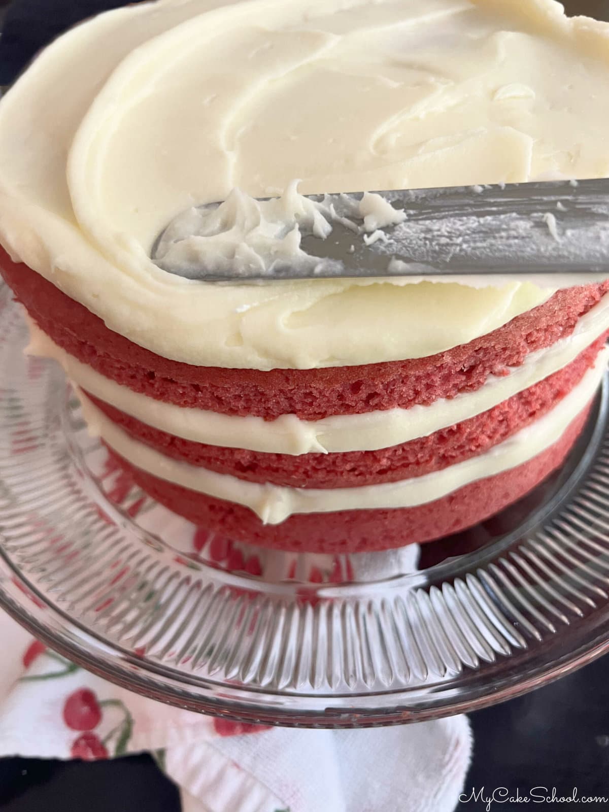 Frosting the filled raspberry cake with cream cheese frosting