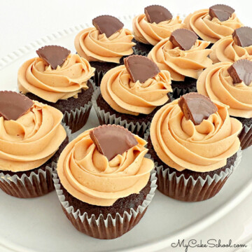 Chocolate cupcakes with peanut butter frosting, topped with Reese's cups on white platter