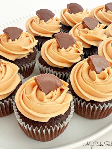 Chocolate cupcakes with peanut butter frosting, topped with Reese's cups on white platter