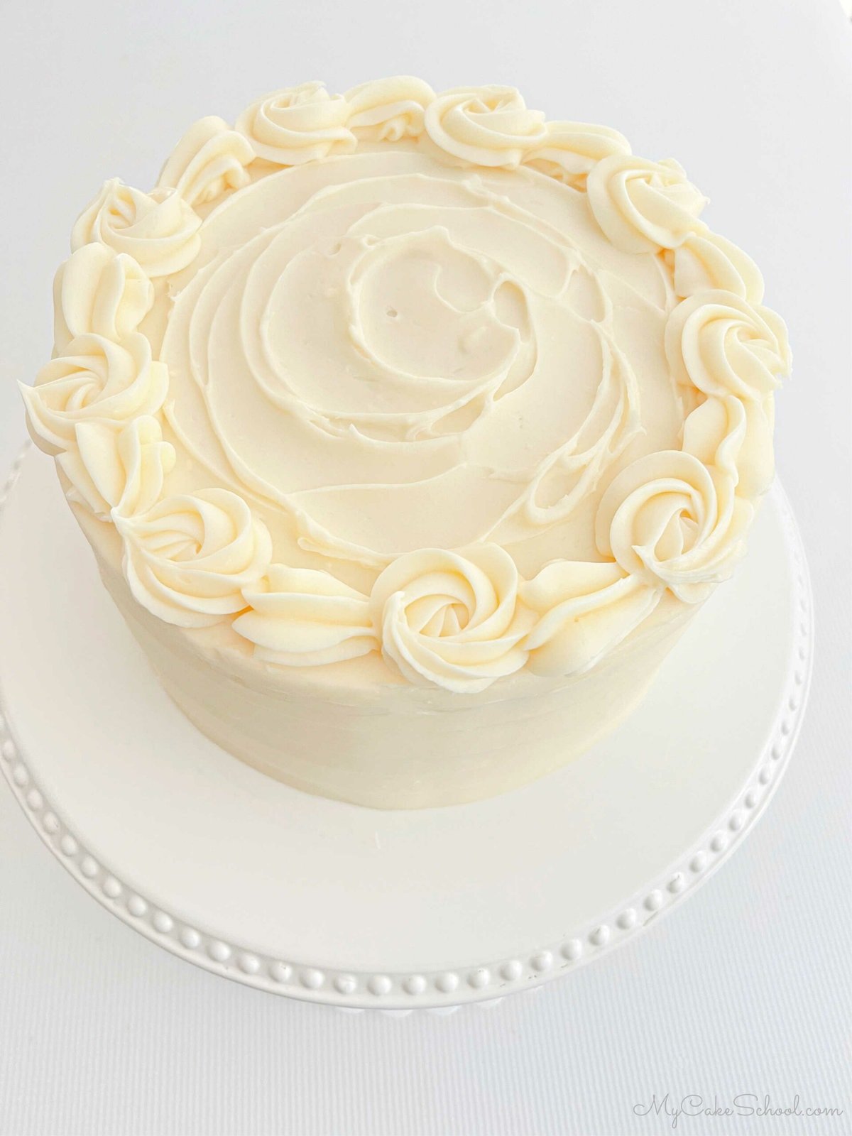 Top view of the frosted Orange Cake, which is decorated with a border of piped buttercream rosettes and shells.
