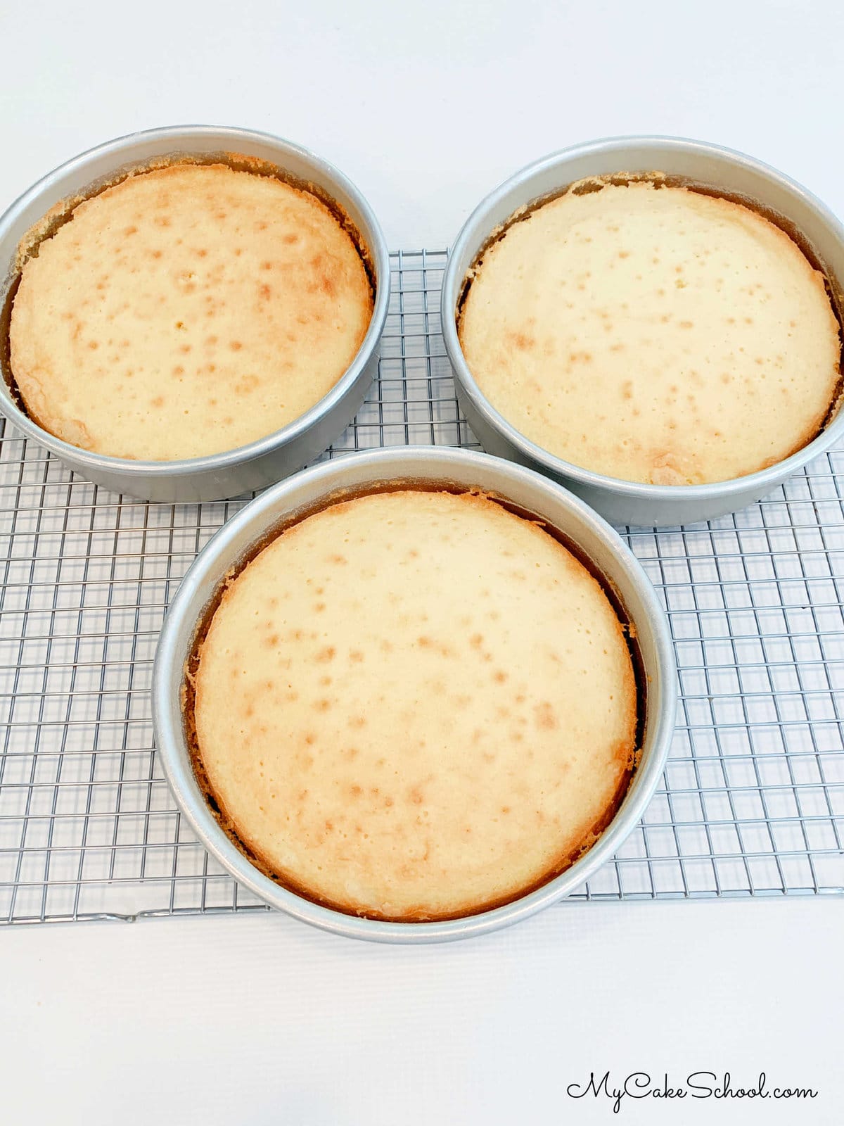 Pound cake layers cooling in pans on a cooling rack