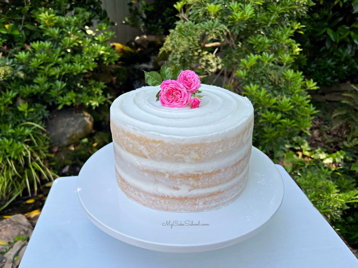 Semi-Naked Cake on a cake pedestal, topped with pink roses