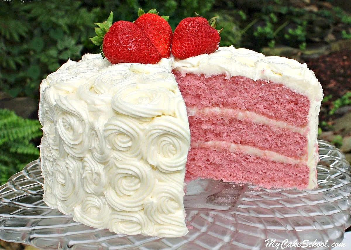 Sliced strawberry layer cake on pedestal.