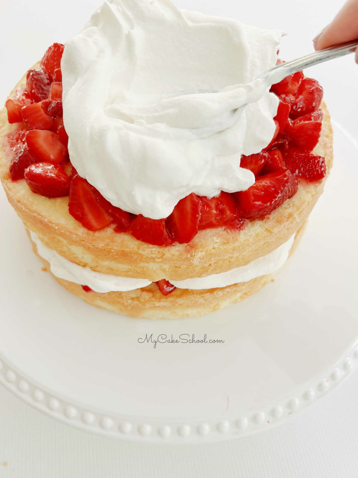 Spreading whipped cream over strawberries and pound cake