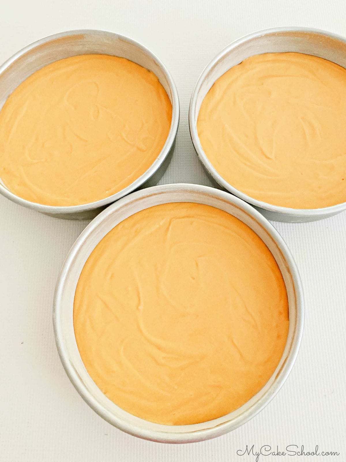 Orange cake batter in pans