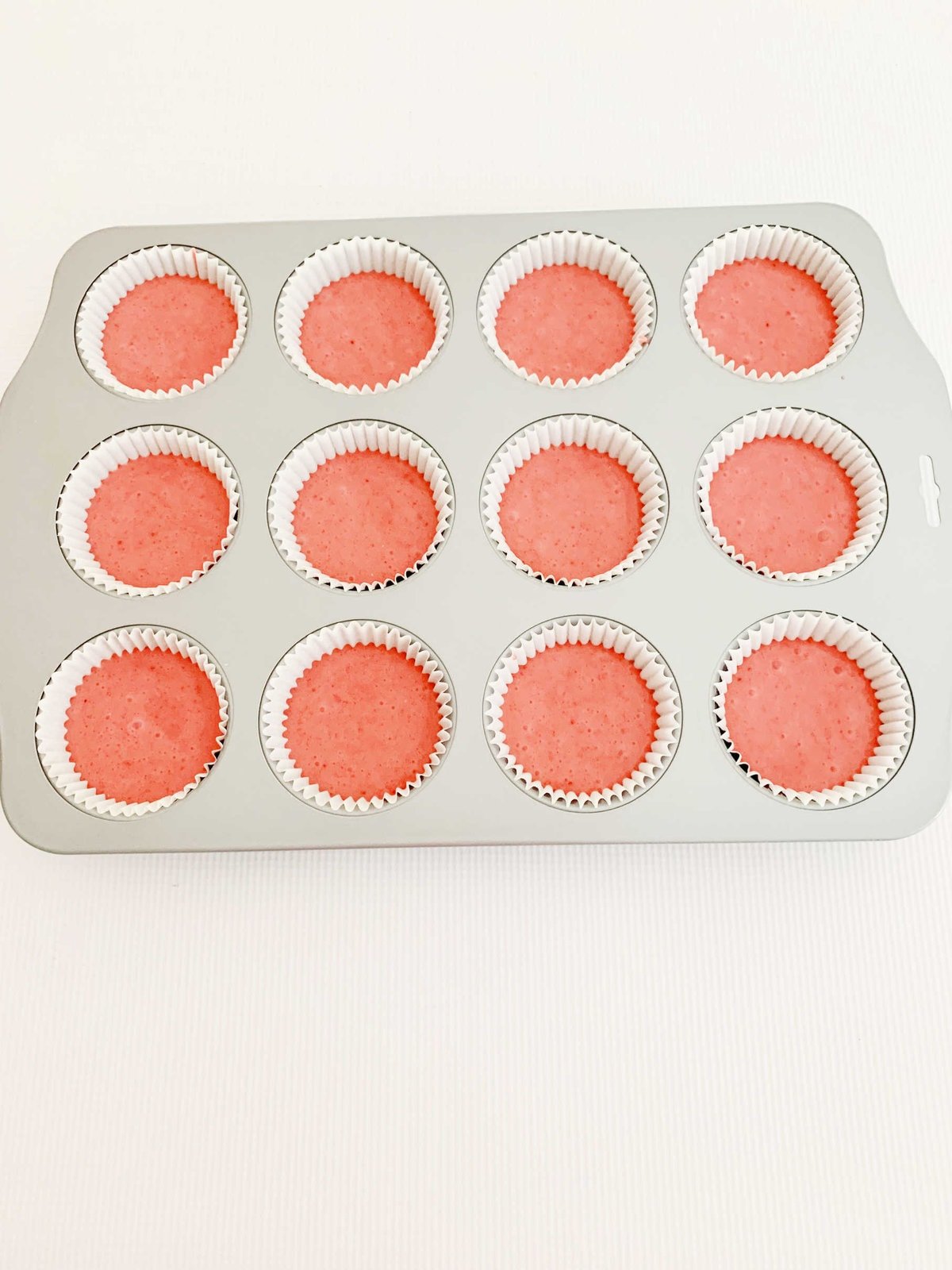 Cupcake liners filled with strawberry cupcake batter