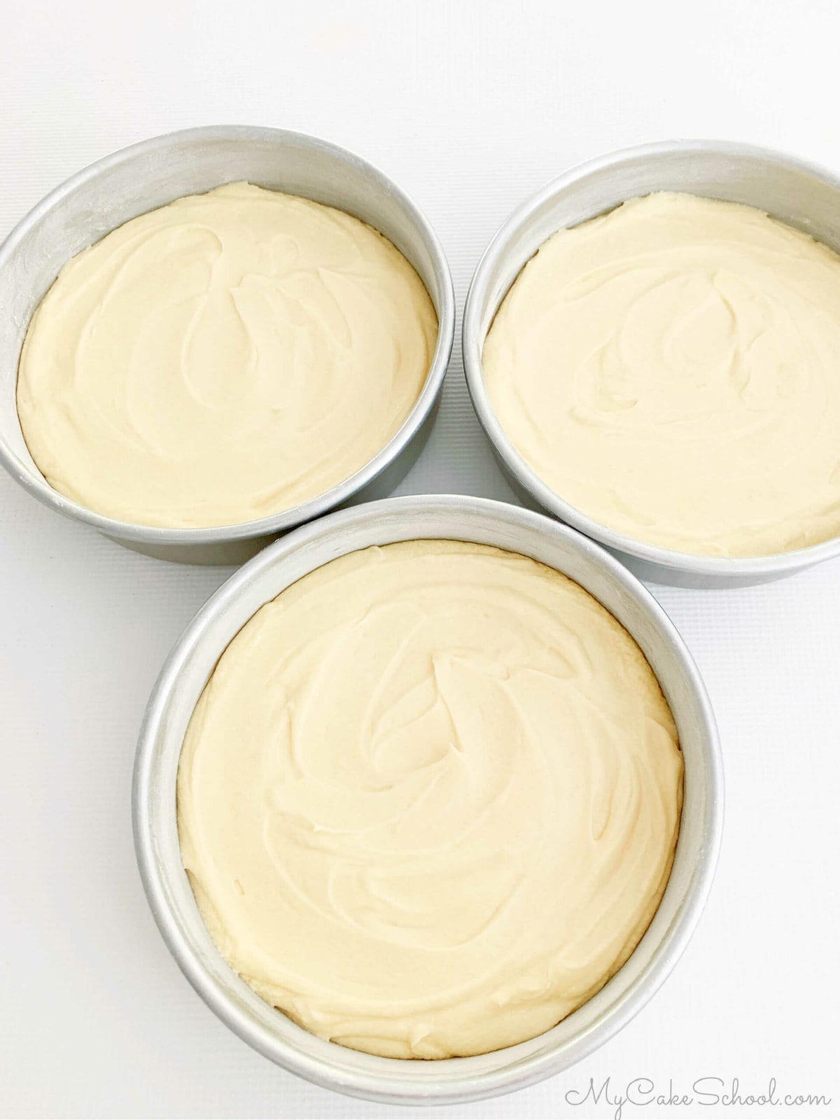 Three 8 inch round cake pans filled with pound cake batter